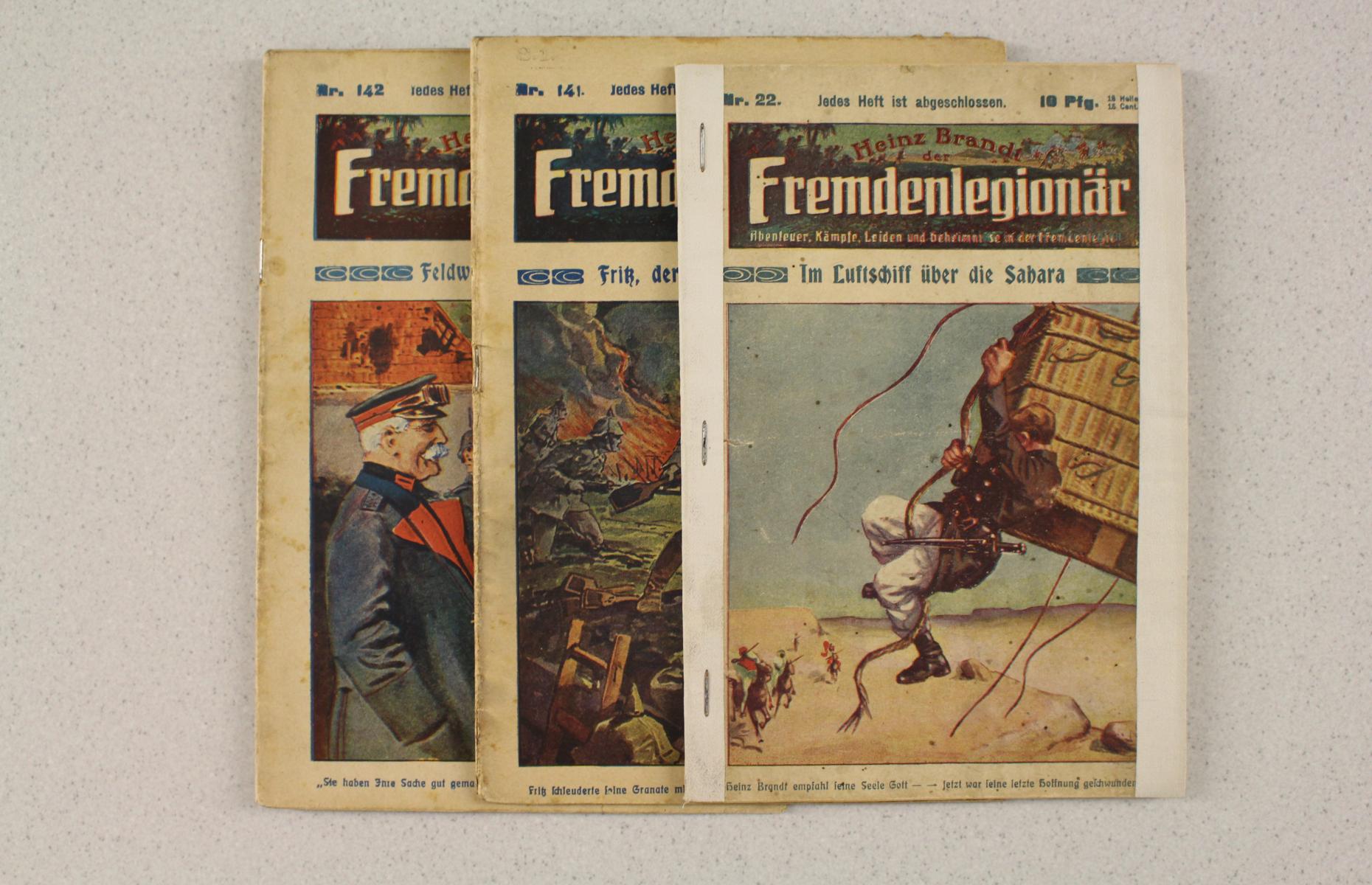 Drei Ausgaben der Heftreihe &quot;Heinz Brandt der Fremdenlegionär&quot; in Frontansicht. Die Cover der Hefte zeigen neben den Titel eine farbige Illustration.