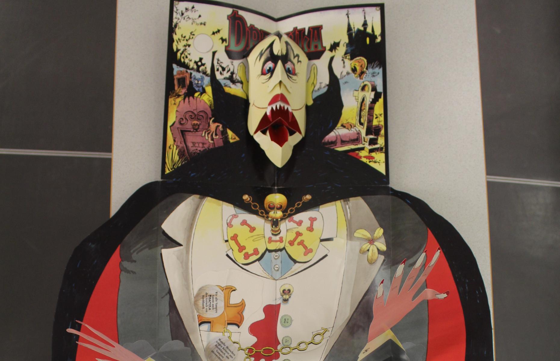 Oberer Teil des vollständig aufgeklappten Pop-up-Buch &quot;Graf Dracula&quot;. Zu sehen sind der Kopf und die Arme von Graf Dracula.