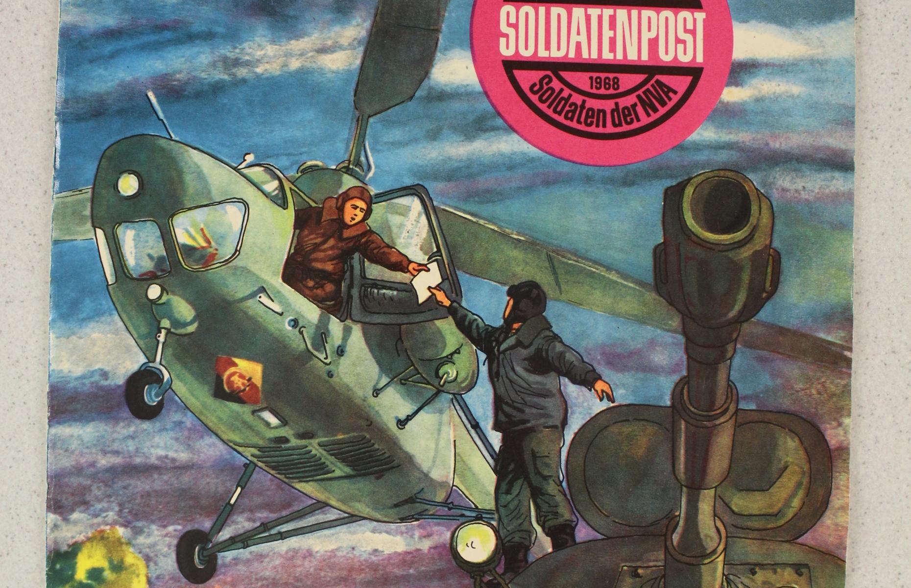Hier sieht man das Cover der Zeitschrift Soldatenpost der NVA. Darauf sieht man Soldaten, einen Hubschrauber und einen Panzer