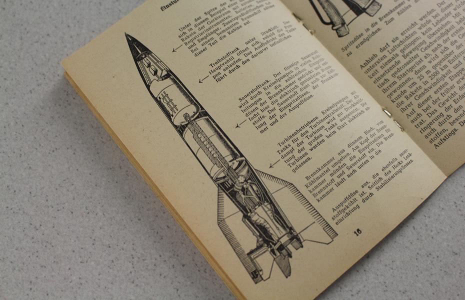 Das Bild zeigt eine Seite des Hefts in Frontalansicht. Die linke Hälfte der Seite wird von der Karikatur einer Rakete eingenommen.