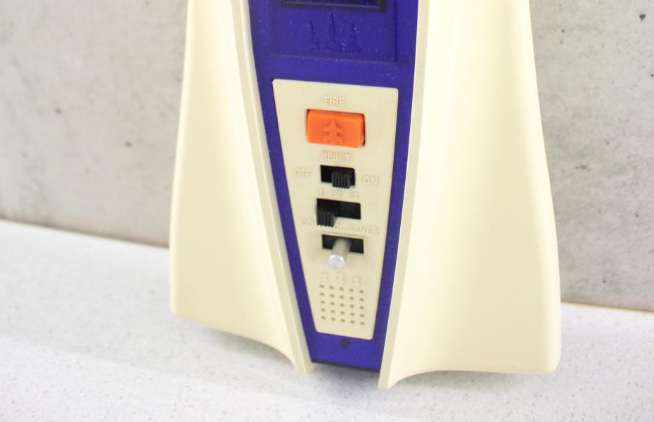 Hier ist der untere Teil des Ufo Master Blasters in weiß, mit einem blauen Mittelteil und Bildschirm zu sehen. Der Hauptsteuerknopf ist orange 
